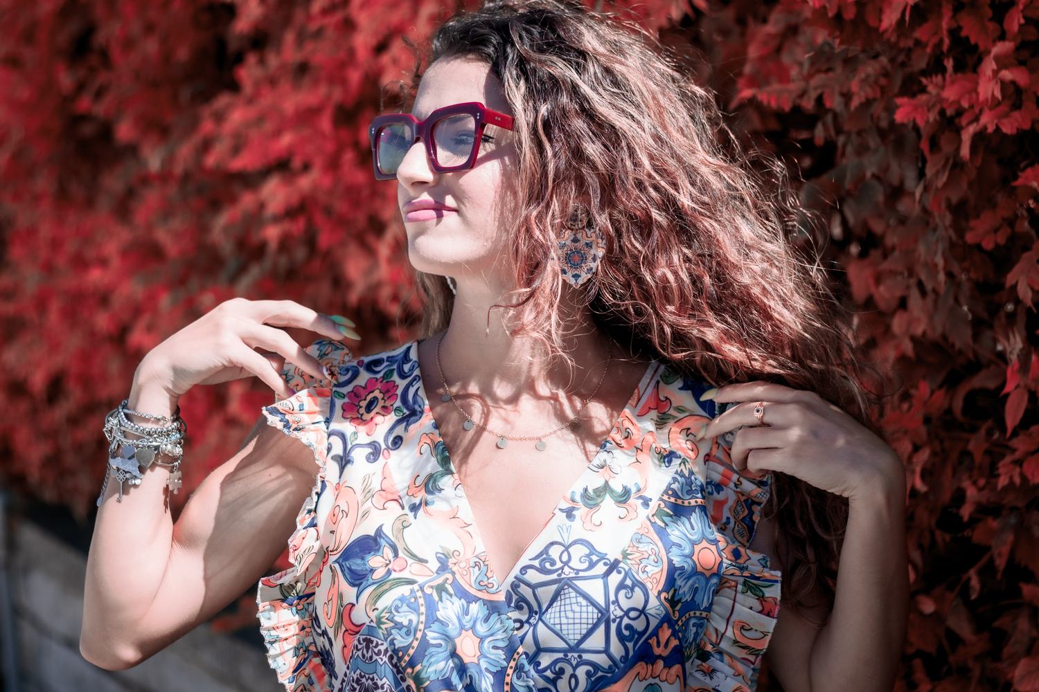 Ragazza con occhiali da vista e capelli ricci su sfondo rosso
